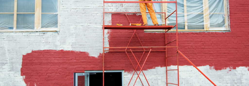 Commercial brick building being painted using scaffolding
