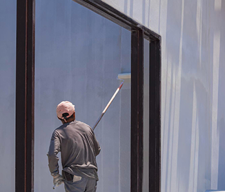 Painter applying paint to large commercial exterior wall