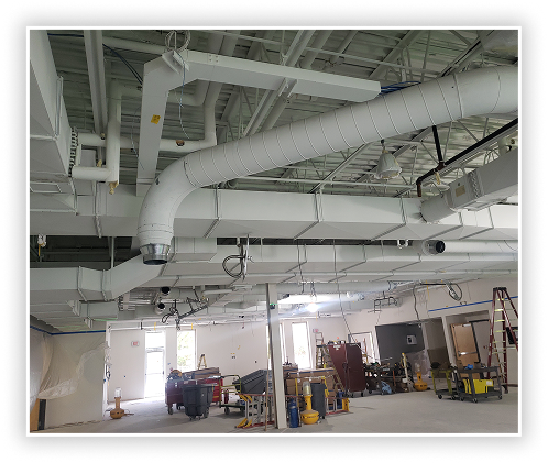 Commercial interior with exposed HVAC ductwork, ventilation system, and open industrial workspace
