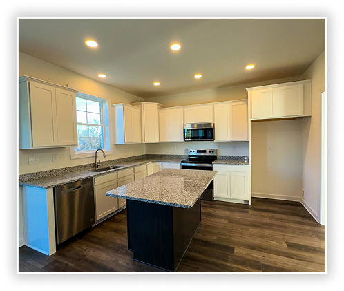 Modern kitchen with white cabinets, granite island, stainless steel appliances, and recessed lighting