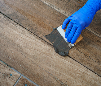 Hand applying filler to repair damaged exterior wood surface